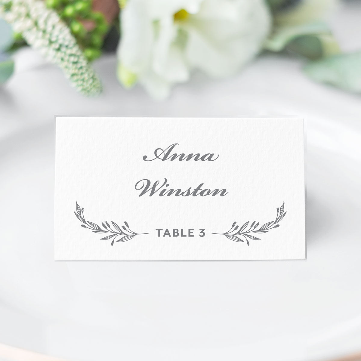 classic crest escort card with grey laurel accents and traditional script and block fonts printed on white cardstock
