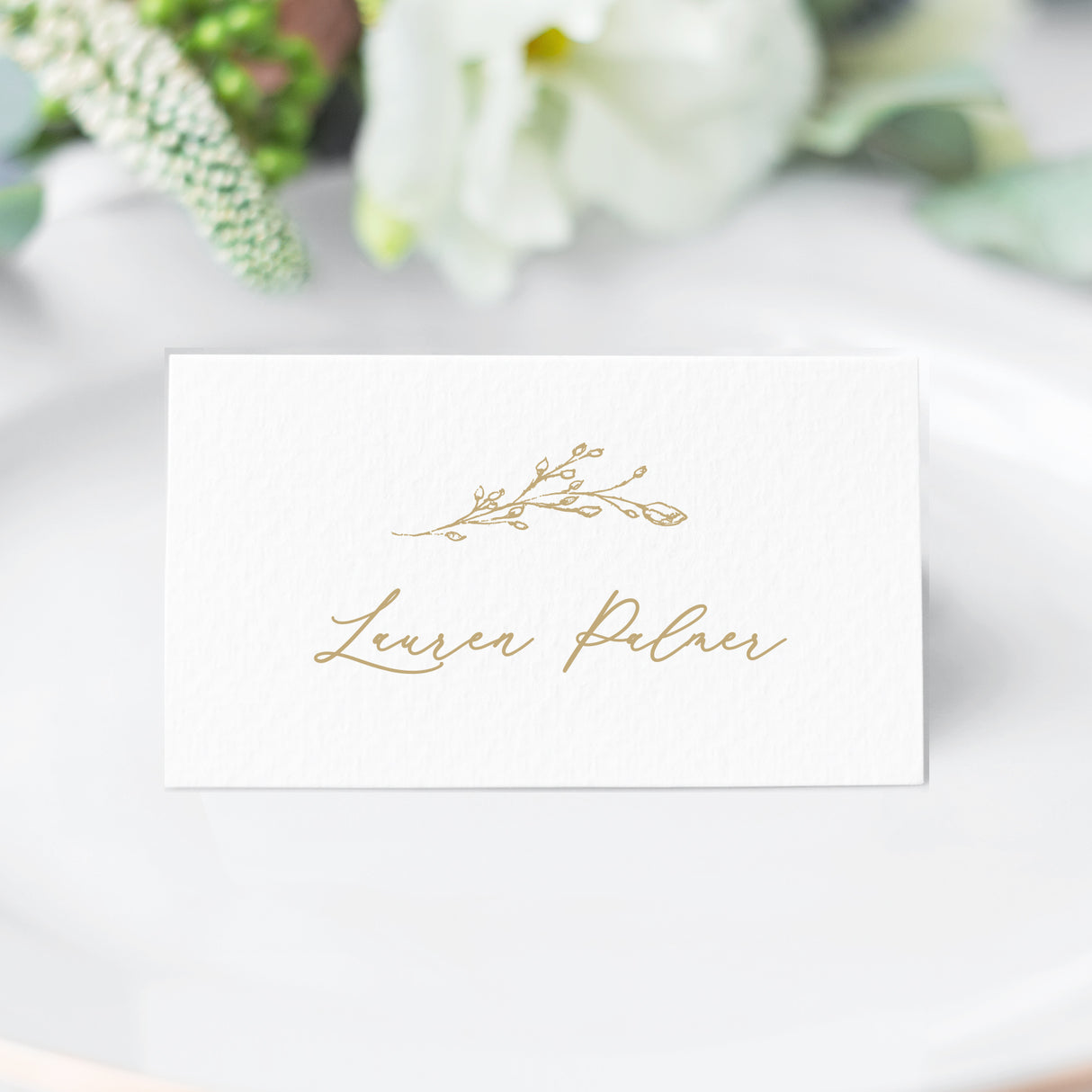 gold crest escort card with a floral branch in a cursive script