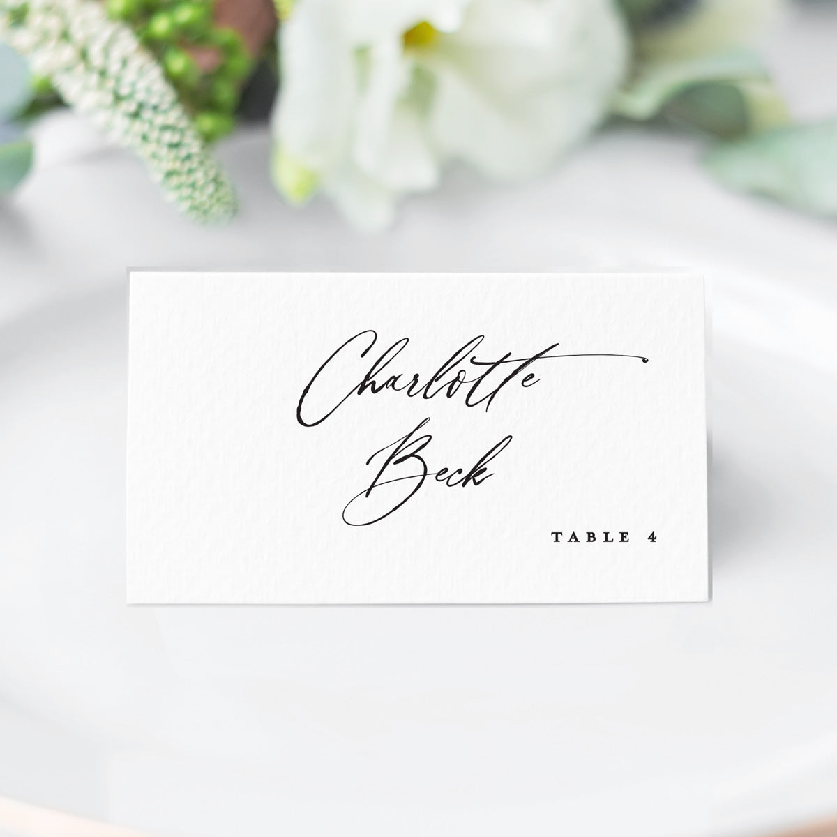 white and black escort card in a modern cursive script font