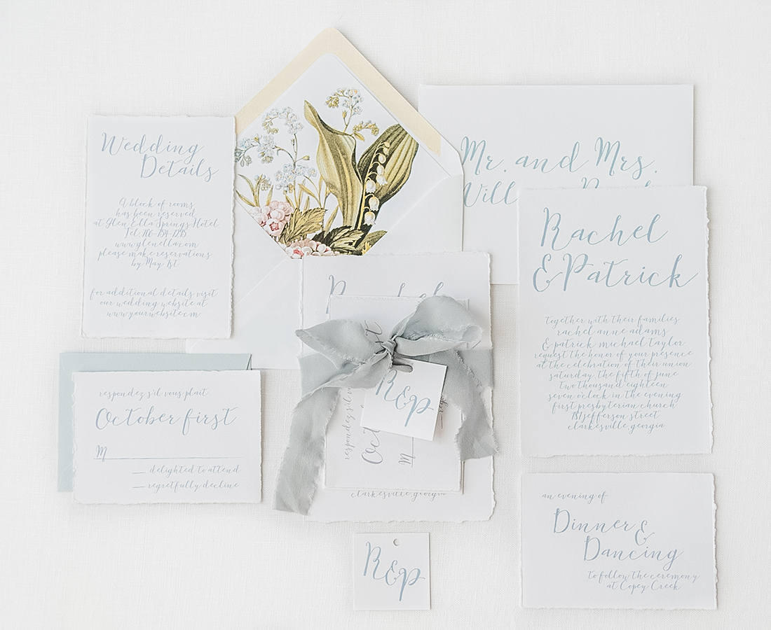 bespoke wedding invitation set with handtorn edges and dusty blue ink ribbon and envelope. Vintage painting envelope liner.