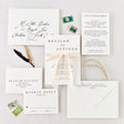 A set of white wedding invitations with minimalist design, including an envelope and RSVP card, displayed on a table with a silk ribbon and stylized text.