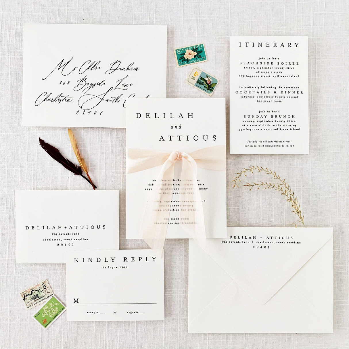 A set of white wedding invitations with minimalist design, including an envelope and RSVP card, displayed on a table with a silk ribbon and stylized text.