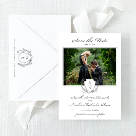 classic wedding save the date card with grey monogram crest and photo of couple with white envelope printed with return address