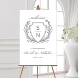 wedding welcome sign with a gray monogrammed crest, the names of the couple, and the wedding date