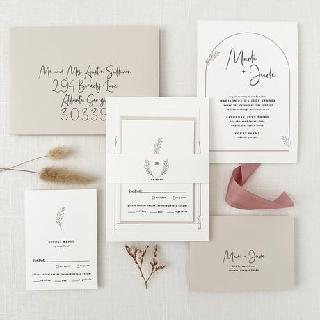 boho dusty rose invitation set printed on white cardstock featuring arch design with monogrammed belly band and taupe envelopes with guest addressing