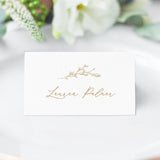 gold crest escort card with a floral branch in a cursive script