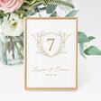 wedding table number featuring a gold crest design personalized with the names and wedding date